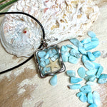 Quadratischer Larimar-Mosaik Anhänger im Edelstahlrahmen mit Seestern-Element und facettierter Bergkristall-Perle, eingebettet in Harz, an schwarzer Lederkette.