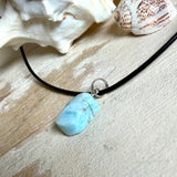 Larimar Freeform Anhänger mit rhodinierter Silberöse an schwarzer Lederkette. Der seltene, kostbare Larimar („Atlantisstein“) zeigt ein lebendiges Muster aus Türkis- und Weißtönen. Beidseitig tragbar, Steingröße ca. 2 x 1 cm, Lederkette 45 cm mit Edelstahl-Karabiner und 5 cm Verlängerung. Natürlicher, maritimer Unikatschmuck.