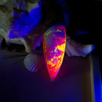 Aurora Flame – fluoreszierender Surfbrett-Anhänger aus Maserholz und leuchtendem Epoxidharz in Rosa, Pink, Orange und Weiß. Der handgefertigte Unikat-Anhänger fluoresziert bei Schwarzlicht in intensiven Farbtönen. Er ist ca. 6,3 x 2 cm groß, wird an einem verstellbaren Lederband (26–45 cm) getragen und ist mit einer silberfarbenen Spacerperle verziert. Ein ausdrucksstarkes Schmuckstück für Menschen mit Persönlichkeit.