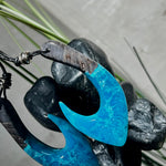 Handgefertigter Maori-Anhänger „Tangaroa Spirit“ in traditioneller Hakenform, gefertigt aus stabilisiertem Maserholz und ozeanblauem Harz. Die polierte Oberfläche bringt die natürlichen Maserungen und das tiefblaue Farbspiel besonders zur Geltung. Symbolisiert Schutz, Stärke und die Verbundenheit zum Meer. Verstellbares Lederband mit Schiebeknoten und dekorativen Holz- sowie Metallperlen – ideal als kraftvoller Talisman oder Geschenk.