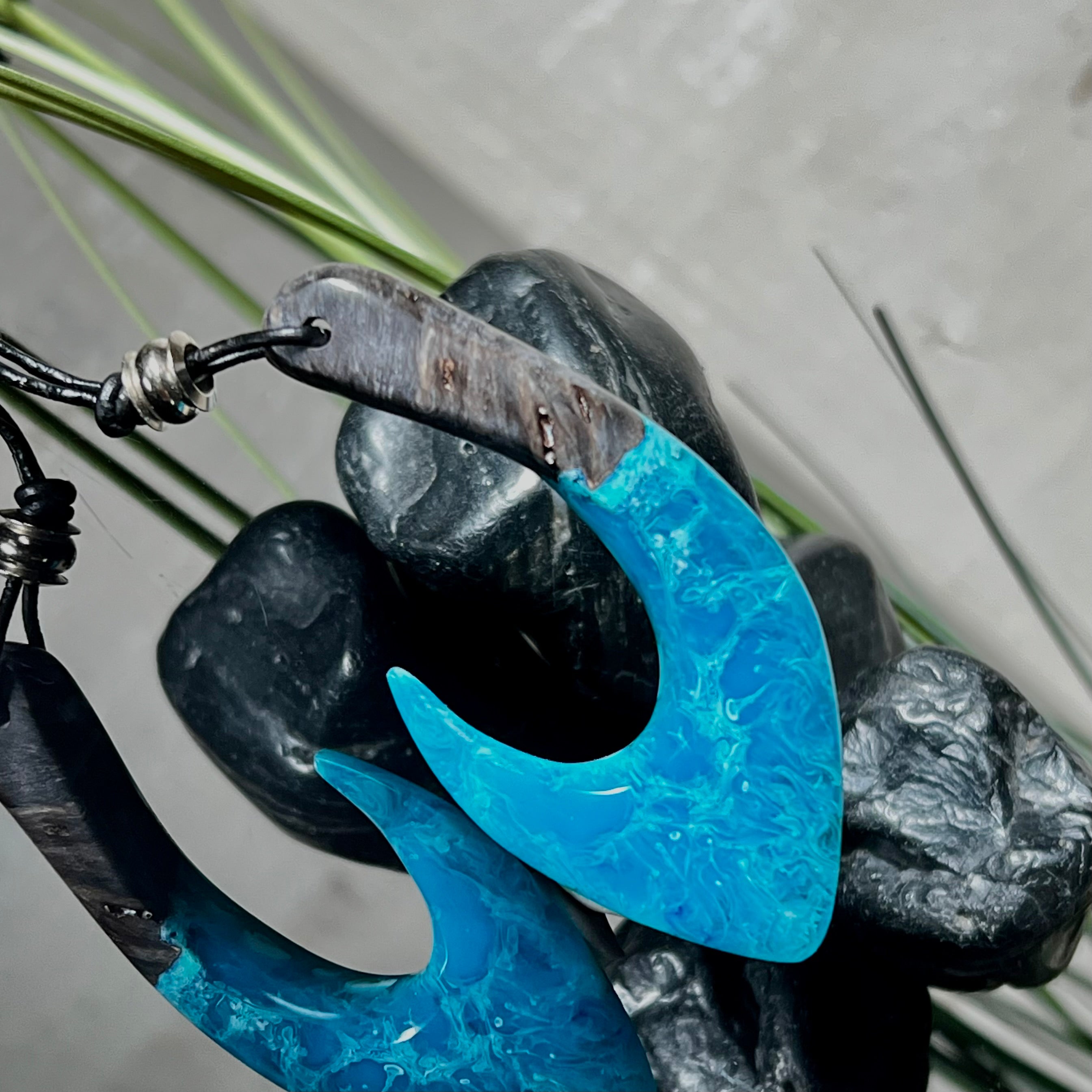 Handgefertigter Maori-Anhänger „Tangaroa Spirit“ in traditioneller Hakenform, gefertigt aus stabilisiertem Maserholz und ozeanblauem Harz. Die polierte Oberfläche bringt die natürlichen Maserungen und das tiefblaue Farbspiel besonders zur Geltung. Symbolisiert Schutz, Stärke und die Verbundenheit zum Meer. Verstellbares Lederband mit Schiebeknoten und dekorativen Holz- sowie Metallperlen – ideal als kraftvoller Talisman oder Geschenk.