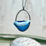 Ovale Halskette „Ocean Crest“ mit 3D-Welle: handgefertigter Harz-Anhänger in Silber-Legierung, Farbverlauf von Tiefblau zu Türkis mit weißer Schaumkrone. Größe ca. 3,9 × 2,3 cm, an einer ca. 56 cm langen versilberten Kette. Glänzende Oberfläche, maritimer Look, Unikat-Handarbeit.