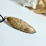 Handgefertigte Surfbrett Kette aus Maserholz und türkisfarbenem Resin mit Edelstahl Anhängerschlaufe an schwarzer Lederkette mit Karabiner und Verlängerung. Filigraner Ocean Anhänger inspiriert von Meer und Wellen, natürlicher Unikat Schmuck für Damen und Herren.