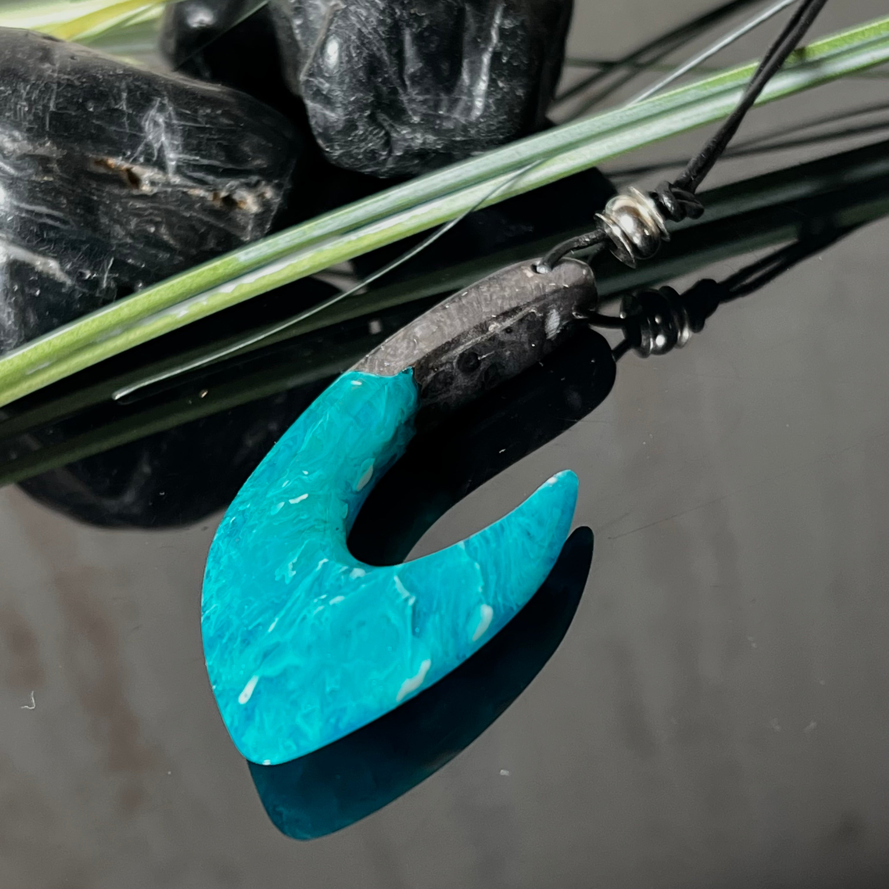 Handgefertigter Maori-Anhänger „Tangaroa Spirit“ in traditioneller Hakenform, gefertigt aus stabilisiertem Maserholz und ozeanblauem Harz. Die polierte Oberfläche bringt die natürlichen Maserungen und das tiefblaue Farbspiel besonders zur Geltung. Symbolisiert Schutz, Stärke und die Verbundenheit zum Meer. Verstellbares Lederband mit Schiebeknoten und dekorativen Holz- sowie Metallperlen – ideal als kraftvoller Talisman oder Geschenk.