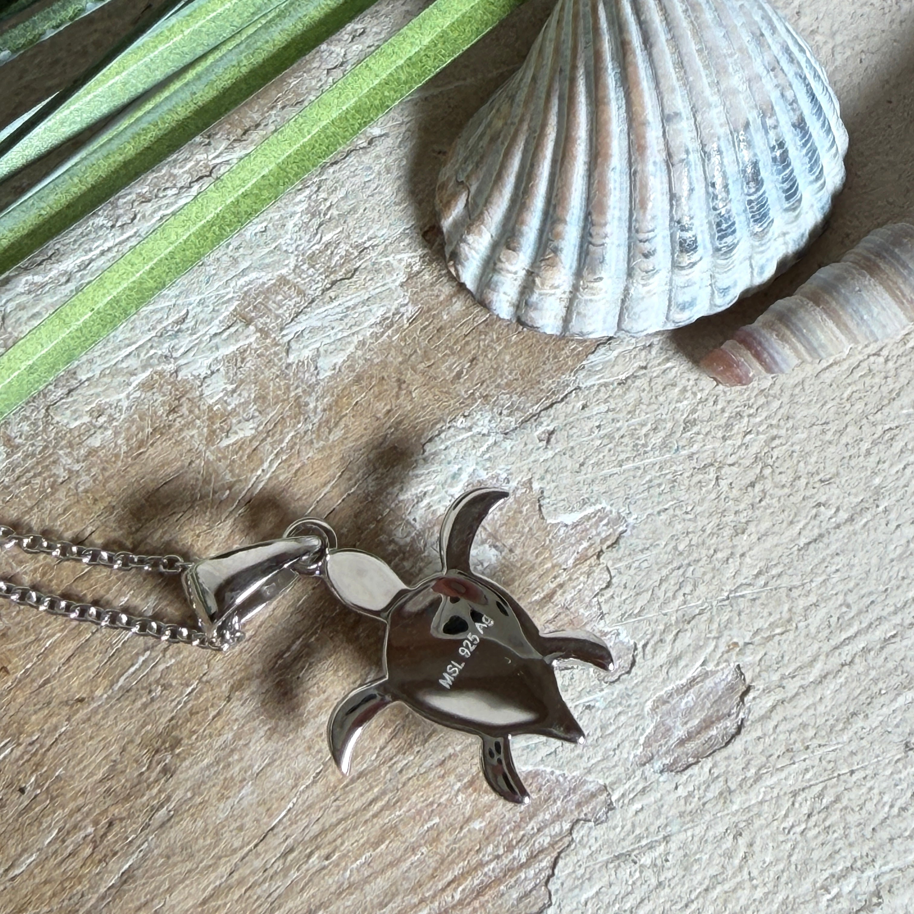 Feine Schildkröten-Kette aus rhodiniertem 925 Silber. Im Panzer des Anhängers liegt ein tropfenförmiger Larimar in hellem Blau. Der Anhänger ist ca. 22 x 18 mm groß und hängt an einer 45 cm langen, 1 mm starken Silberkette.