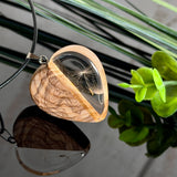 Pusteblumen Herzanhänger aus Olivenholz und glasklarem Epoxidharz, echte Löwenzahnsamen im Harz schwebend, schwarze Lederkette, handgefertigter Naturschmuck mit Spiegelung, dunkler Hintergrund