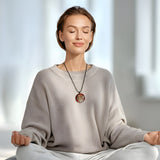 Handgefertigtes Medaillon aus klarem Epoxidharz mit kunstvollem rot-silber-weißen Farbverlauf und einem goldenen Samen des Lebens Symbol in der Mitte. Das spirituelle Schmuckstück strahlt Harmonie, Wachstum und Schutz aus. Rückseite mit individueller Harzstruktur, Vorderseite transparent glänzend. Anhänger mit verstellbarem schwarzen Baumwollband, auf hellem Hintergrund mit grünen Blätterni dekorativ inszeniert.