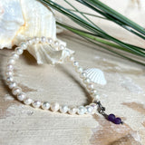 Handgefertigtes Armband „Sea Harmony“ mit schimmernden Süßwasserperlen (Ø ca. 6–7 mm), jede Perle ein Unikat. Auf elastischem Band gefädelt, mit einem filigranen Charmanhänger aus  Amethyst-Perlen, befestigt an einem robusten Edelstahl-Karabiner. Ein Schmuckstück voller Eleganz, maritimer Harmonie und symbolischer Tiefe – ideal als Geschenk oder als stilvolles Accessoire.