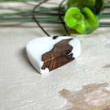 Herzanhänger „Pure Heart“ aus Maserholz und weißem Epoxidharz. Handgefertigtes Unikat mit kontrastreichem Design – die natürliche Maserung des Holzes trifft auf die klare Reinheit von Weiß. Größe ca. 3,5 × 3,5 cm. Verstellbares Lederband (23–41 cm) mit Holzperlen. Ein edles Schmuckstück, inspiriert von Natur und Liebe.