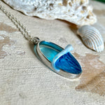 Ovale Halskette „Ocean Crest“ mit 3D-Welle: handgefertigter Harz-Anhänger in Silber-Legierung, Farbverlauf von Tiefblau zu Türkis mit weißer Schaumkrone. Größe ca. 3,9 × 2,3 cm, an einer ca. 56 cm langen versilberten Kette. Glänzende Oberfläche, maritimer Look, Unikat-Handarbeit.