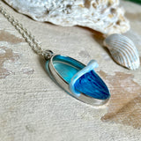 Ovale Halskette „Ocean Crest“ mit 3D-Welle: handgefertigter Harz-Anhänger in Silber-Legierung, Farbverlauf von Tiefblau zu Türkis mit weißer Schaumkrone. Größe ca. 3,9 × 2,3 cm, an einer ca. 56 cm langen versilberten Kette. Glänzende Oberfläche, maritimer Look, Unikat-Handarbeit.