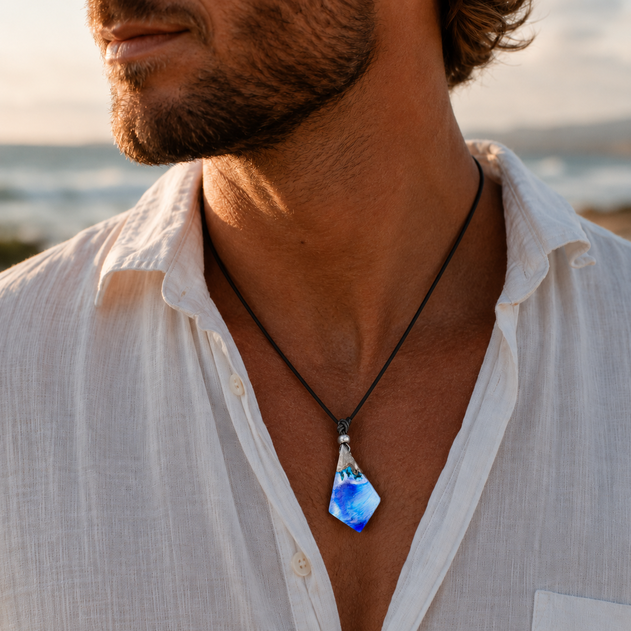 KI-Tragebild WAVE WHISPER – handgefertigter Holz-Harz-Anhänger aus Maserholz und blau-weißem Epoxidharz, transparent schimmernder maritimer Naturschmuck am schwarzen Lederband, getragen von einem Mann im sommerlichen Küstenlook.