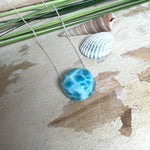 Feine Kette mit rundem Larimar-Cabochon in AA-Qualität. Der ca. 20 mm große Stein zeigt ein intensives Blau mit hellen, netzartigen Zeichnungen und ist mittig mit einer 2,5 mm Bohrung versehen, durch die eine zarte 925 Silberkette (45 cm, ca. 1 mm stark) geführt wird. 