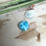 Feine Kette mit rundem Larimar-Cabochon in AA-Qualität. Der ca. 20 mm große Stein zeigt ein intensives Blau mit hellen, netzartigen Zeichnungen und ist mittig mit einer 2,5 mm Bohrung versehen, durch die eine zarte 925 Silberkette (45 cm, ca. 1 mm stark) geführt wird. 