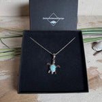 Feine Schildkröten-Kette aus rhodiniertem 925 Silber. Im Panzer des Anhängers liegt ein tropfenförmiger Larimar in hellem Blau. Der Anhänger ist ca. 22 x 18 mm groß und hängt an einer 45 cm langen, 1 mm starken Silberkette.