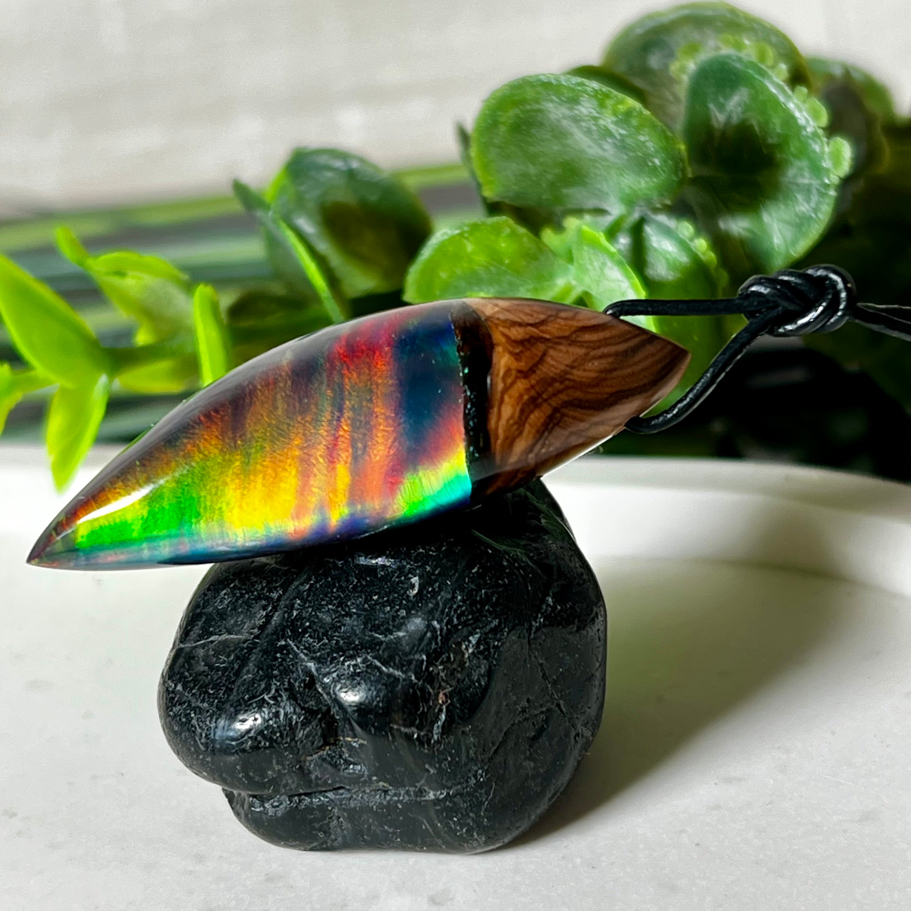 Der handgefertigte Anhänger „Celestial Flame“ kombiniert warmes Olivenholz mit glasklarem Harz und irisierendem Opal. Das einzigartige Farbspiel erinnert an Polarlichter und verleiht dem Schmuckstück eine mystische Tiefe. Die Oberfläche ist glatt poliert, der Anhänger wird an einem verstellbaren Lederband getragen – ein ausdrucksstarkes Unikat für alle, die Naturmaterialien und kreative Farben lieben.