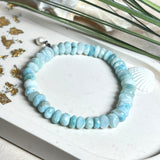 Handgefertigtes Armband aus seltenem Larimar mit facettierten, türkis-blauen Edelsteinperlen (Ø ca. 6–7 mm), elastischem Band und einem zarten Süßwasserperlen-Charm an Edelstahlkarabiner. Der wertvolle Larimar, auch „Stein des Atlantis“ genannt, gilt als Edelstein der Ruhe und Meeresverbundenheit.