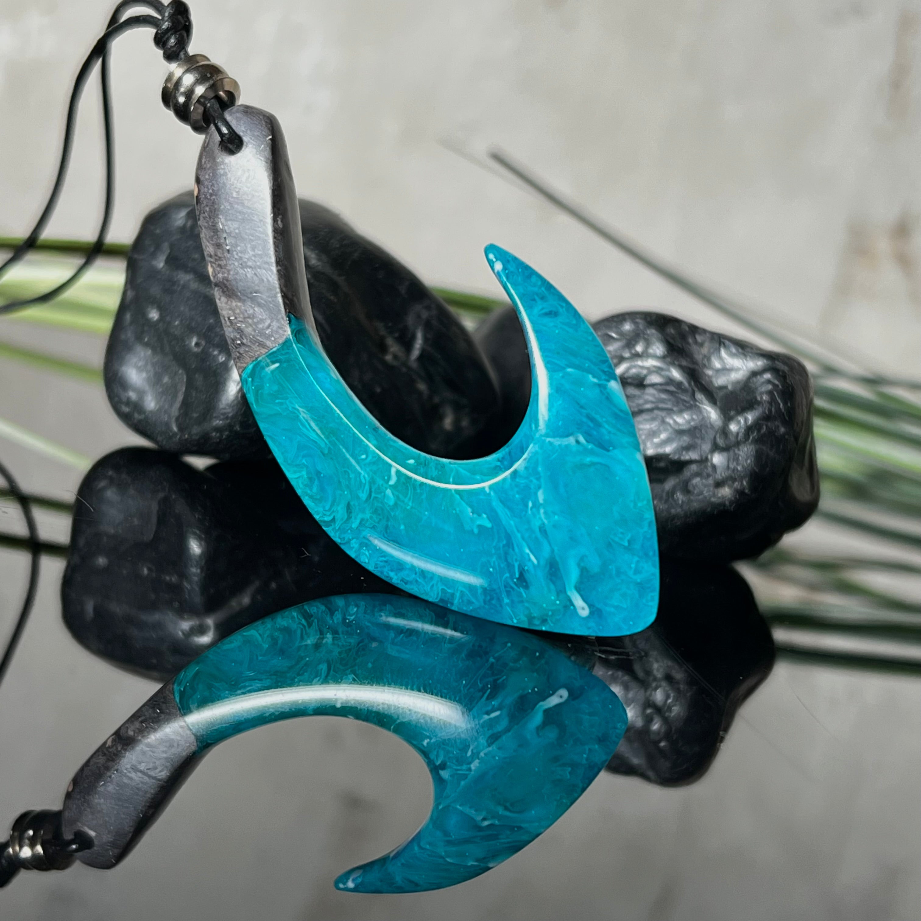 Handgefertigter Maori-Anhänger „Tangaroa Spirit“ in traditioneller Hakenform, gefertigt aus stabilisiertem Maserholz und ozeanblauem Harz. Die polierte Oberfläche bringt die natürlichen Maserungen und das tiefblaue Farbspiel besonders zur Geltung. Symbolisiert Schutz, Stärke und die Verbundenheit zum Meer. Verstellbares Lederband mit Schiebeknoten und dekorativen Holz- sowie Metallperlen – ideal als kraftvoller Talisman oder Geschenk.