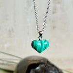 Halskette mit Malachit-Herz: kleiner, gewölbter Herzanhänger aus intensiv grün gebändertem Malachit, ca. 16 x 14 x 10 mm, in hochglanzpolierter, rhodinierter 925 Silberfassung an feiner Ankerkette aus Silber.