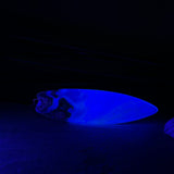 Surfbrett-Anhänger aus Maserholz und blau-weißem Epoxidharz, hochglanzpoliert, ca. 6,5 × 2 cm. An schwarzer Lederkette mit Edelstahl-Karabiner und 5-cm-Verlängerung; Edelstahl-Öse. Im Tageslicht lagunenblau, unter Schwarzlicht fluoreszierend – ideal als Party-/Festival-Schmuck. Handgefertigtes Unikat, Lieferung in edler Schmuckbox.