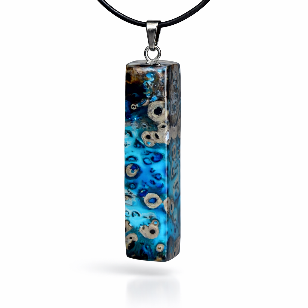 Rechteckiger Stabanhänger aus Maserholz und glasklarem Epoxidharz in tiefen Blau- und Türkistönen mit organischer Lagunen/Riff-Optik. Hochglanzpoliert, ca. 5,3 × 1,2 cm. Der Anhänger hängt an einer schwarzen Lederkette mit Edelstahl-Karabiner und 5-cm-Verlängerung (45 + 5 cm); die Anhängerschlaufe ist ebenfalls aus Edelstahl. Handgefertigtes Unikat, Lieferung in edler Schmuckbox – maritimer Look.
