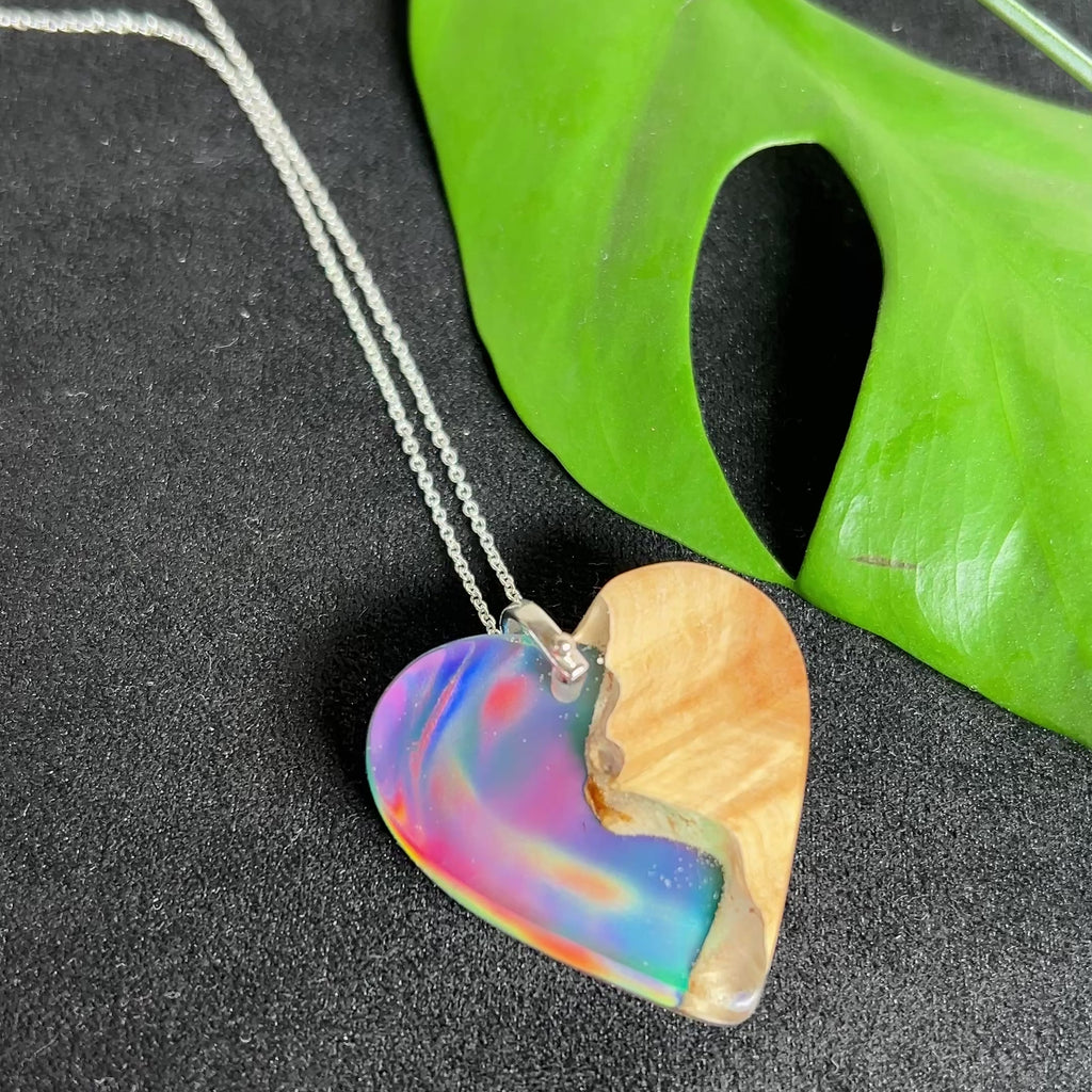 Handgefertigter Herzanhänger aus Maserholz und schimmerndem Opalharz, inspiriert von den Farben der Aurora Borealis. Das Holz zeigt eine feine Maserung, das Harz leuchtet in Rosa-, Blau- und Violetttönen. Mit zarter 925 Silber-Ankerkette (1 mm stark, 45 cm lang) und Silberöse. Ein edles Unikat in liebevoller Handarbeit gefertigt.